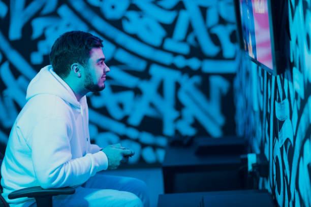 istock Young man plays on game console with gamepad sitting on chair 1397808731