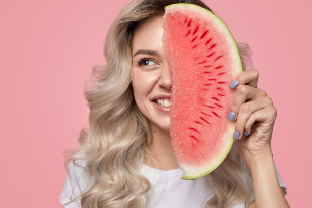 istock Smiling young woman smiling while holding watermelon slice near face in studio 1397808883