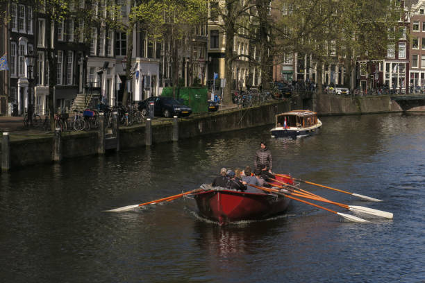 a unique experience as a rowboat powered by tourists navigates the Singel Canal in the historic center city of Amsterdam in the springtime