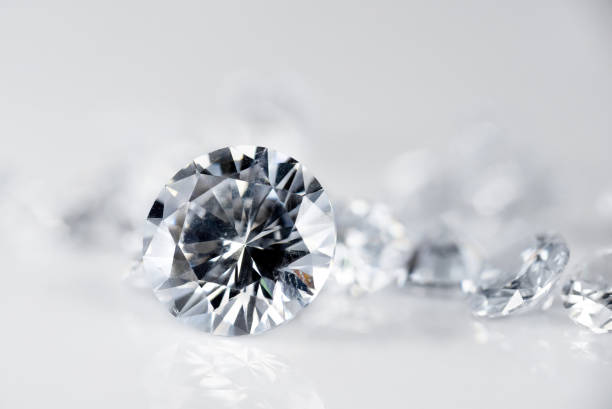diamant taille brillant maintenu par une pince à épiler sur fond blanc - precious gem photos photos et images de collection