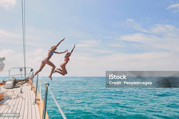 Carefree Excited Young Women Jumping From Boat To Swim In The Ocean Two Friends On A Holiday Cruise Together Jumping From Boat Into The Ocean To Swim Excited Young Women Jumping Off Boat Together Stock Photo - Download Image Now