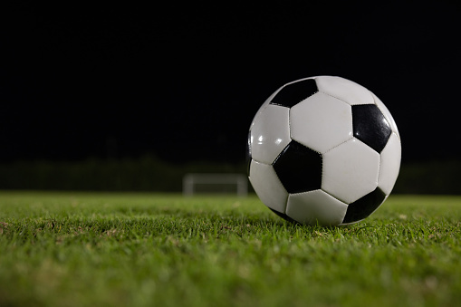 Soccer ball on the ground at a football field at night - sports concepts
