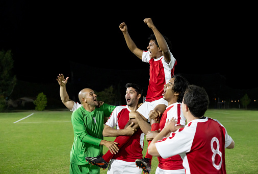 Happy group of Latin American soccer players celebrating a victory in the field - sports concepts
