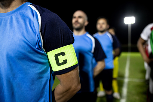 Close-up on a captain band on the arm of a soccer player in line at the field - sports concepts