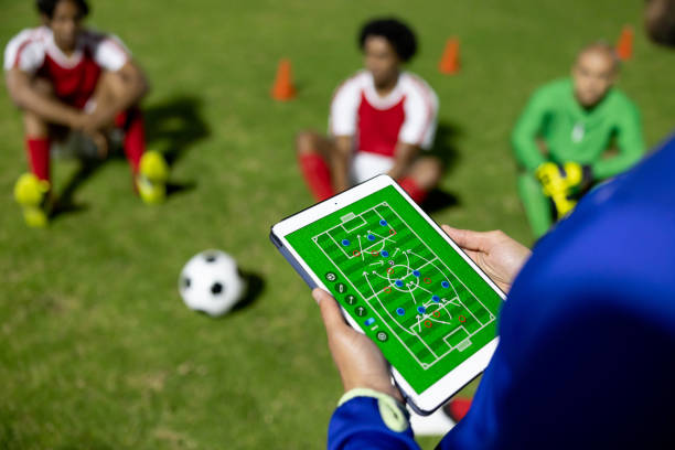 Soccer coach explaining his strategy to a group of players Soccer coach using a tablet computer while explaining his strategy to a group of players in the field at nighttime digitain sportsbook stock pictures, royalty-free photos & images