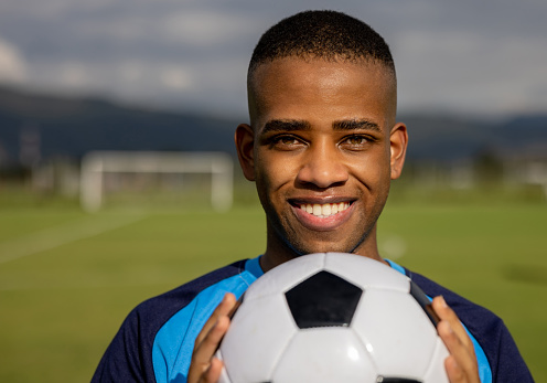 Portrait of a happy African American soccer player holding a soccer ball and smiling - sports concepts
