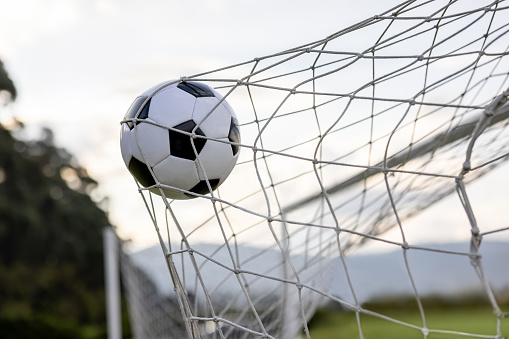 Close-up on a soccer ball hitting the goal net after scoring - scoring a goal concepts
