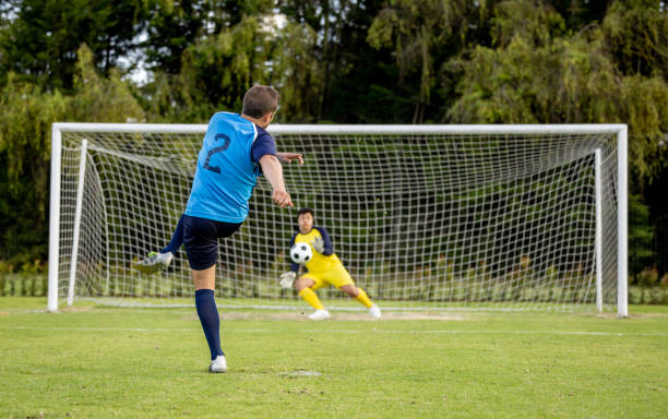 soccer player taking a penalty kick while playing a game - soccer player kicking soccer goalie imagens e fotografias de stock