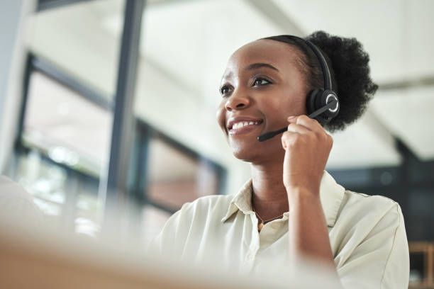 zdjęcie pod niskim kątem przedstawiające atrakcyjną młodą agentkę call center siedzącą samotnie w biurze i korzystającą z komputera - customer service representative service african descent receptionist zdjęcia i obrazy z banku zdjęć