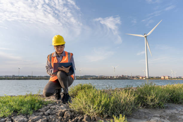 An Asian female engineer squatted on the beach to check the wind turbine data
