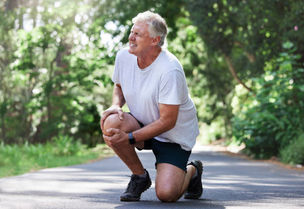 Shot of a mature man experiencing knee pain while exercising outdoors I might have to call the ambulance for this knee stock pictures, royalty-free photos & images