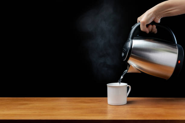 istock Modern electric kettle, cup on wooden table with black background 1397823075