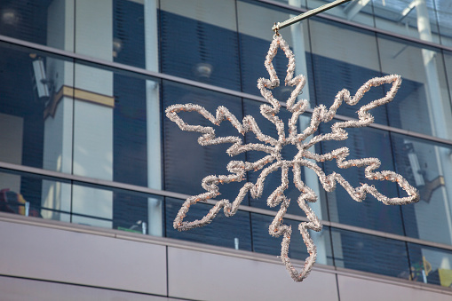 snow flake with lights holiday decoration hanging in streets of San Francisco with office building in background