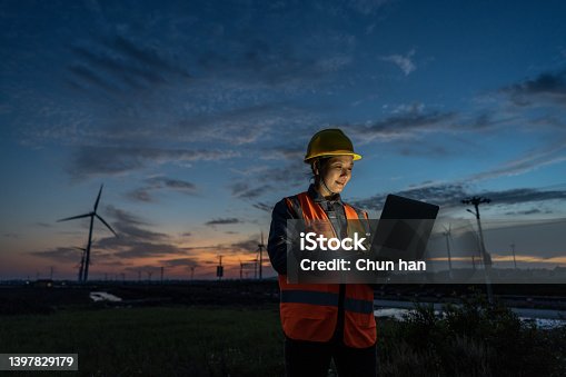 istock An Asian female wind power engineer on the night shift works with a computer under the wind turbine 1397829179