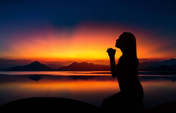 무릎을 꿇고 아름다운 일몰 위에 기도하는 여자의 실루엣 - god sunbeam sunset religion 뉴스 사진 이미지