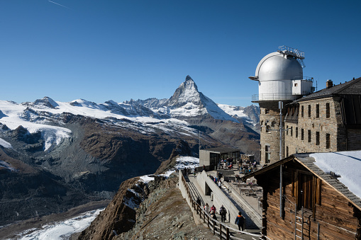 Grindelwald, Switzerland - October 10, 2019: People at the middle station at First peak of Swiss Alps mountain, snow peaks panorama, Bernese Oberland, Europe