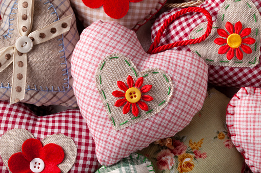 a knitted heart of red thread with an inserted knitting needle on a white background. and a hank of a red knitting thread