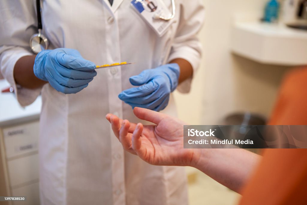Close up shot of healthcare worker's gloved hands holding blister pack of medication Close up shot of healthcare worker's gloved hands handing blister pack of pills to female inmate at a correctional healthcare facility Prison Stock Photo