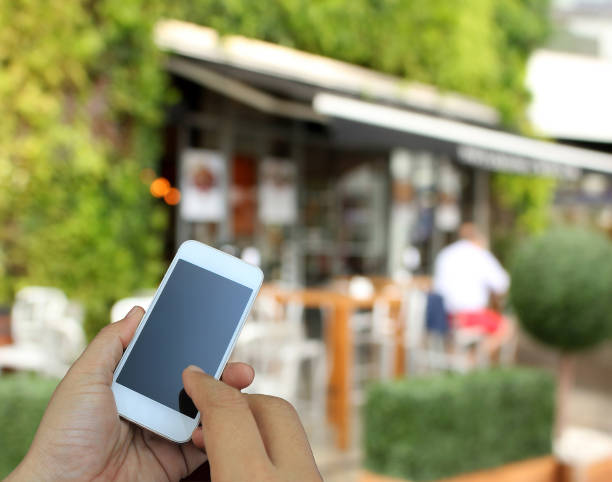 istock hand holding the smartphone on blur restaurant background 1397838732
