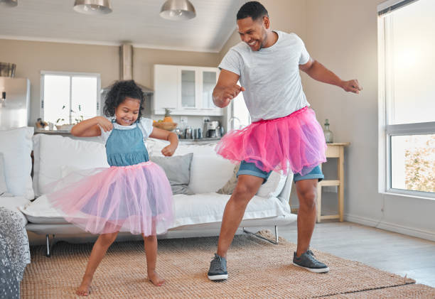 aufnahme eines vaters und einer tochter, die zu hause zusammen im wohnzimmer tanzen - ballettröckchen stock-fotos und bilder