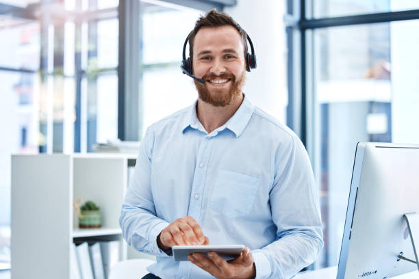 Portrait of a young call centre agent working on a digital tablet in an office