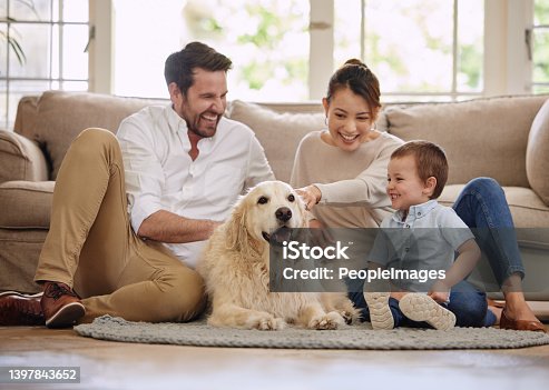 istock Shot of a young family sitting on the living room floor with their dog 1397843652
