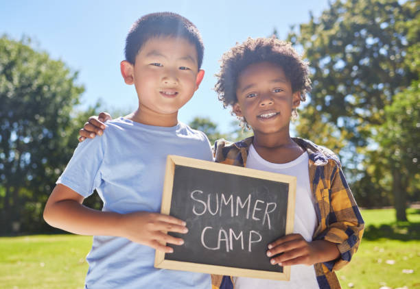 Shot of a two friends holding a sign in a outside in a park Carefree days at summer camp summer camp stock pictures, royalty-free photos & images