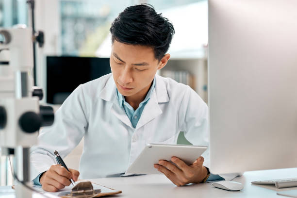 istock Shot of a young scientist using a digital tablet and writing notes while working in a lab 1397843852