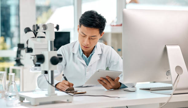 istock Shot of a young scientist using a digital tablet and writing notes while working in a lab 1397843855