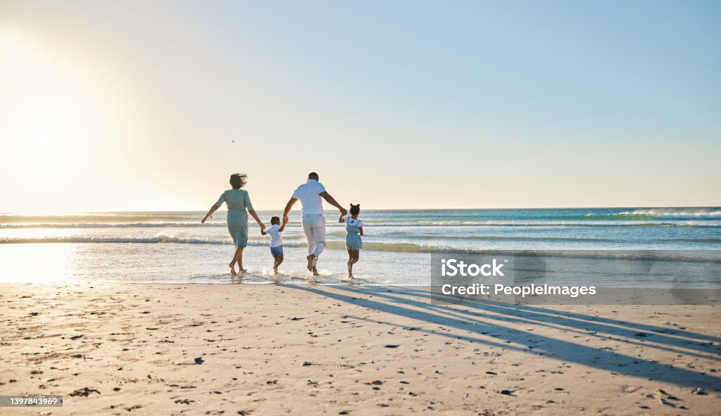 Rearview shot of a happy family walking towards the sea Let's go splish and splash Family Stock Photo