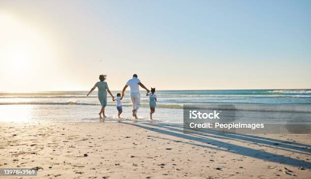 Rearview Shot Of A Happy Family Walking Towards The Sea Stock Photo - Download Image Now