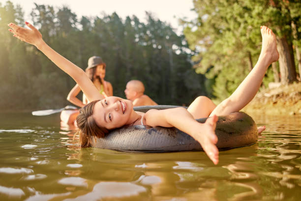 photo d’une jeune femme se relaxant sur un tube gonflable au bord du lac - floatation device flash photos et images de collection