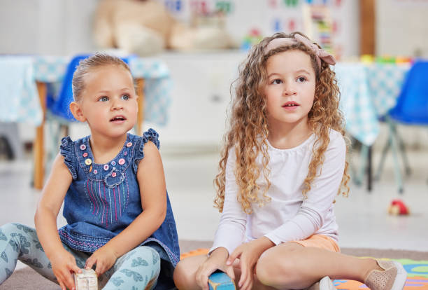 scatto di due bambine sedute una accanto all'altra in classe - elementary age focus on foreground indoors studio shot foto e immagini stock
