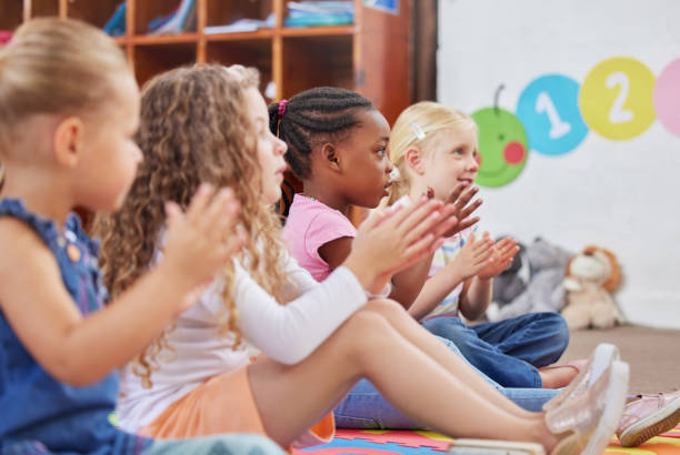Shot of children clapping hands while sitting in class