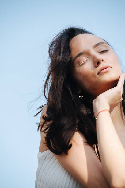 istock Serene brunette with vitiligo face sitting with eyes closed. Over blue sky 1397845824