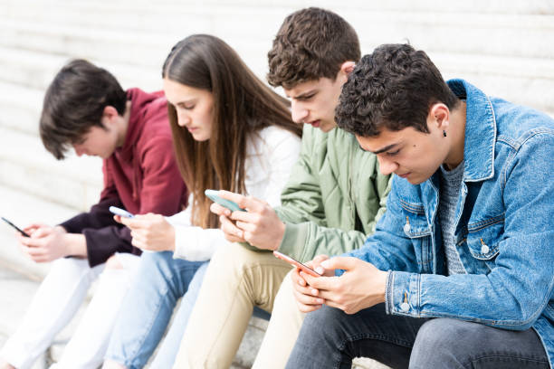 istock Hispanic teenager using phone with friends 1397848298