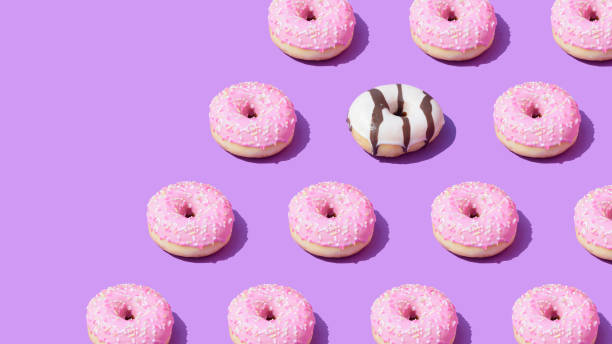 istock Pink and white doughnuts pattern on a purple background with diagonal copy space. 1397854602