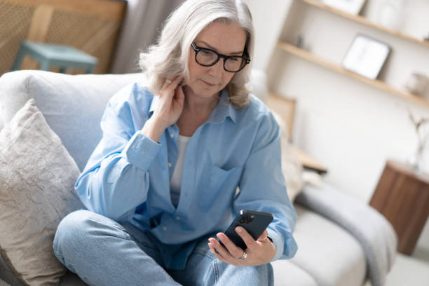 istock Pleasant mature lady resting on couch, using applications on smartphone, chatting in messenger or social network 1397857285