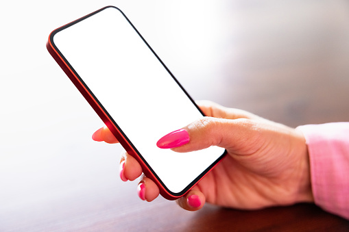 Closeup photo of mobile phone in woman's hand, white empty screen mockup