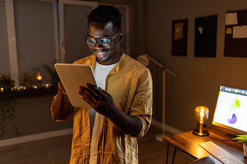 Shot of a young businessman using a digital tablet in an office at night