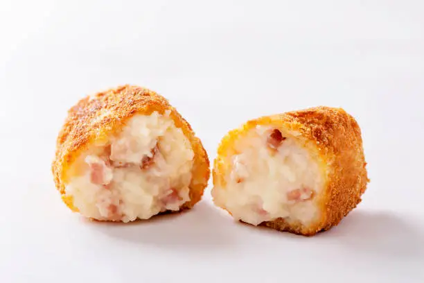 Close up of a sliced ham croquette on white background
