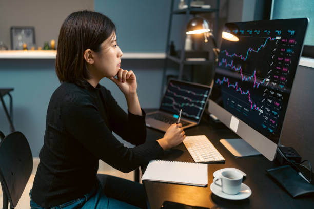 Young woman doing cryptocurrency business trading on her computer at home at nigh A young woman is doing cryptocurrency business trading on her computer at home at nigh. bitcoin trading stock pictures, royalty-free photos & images