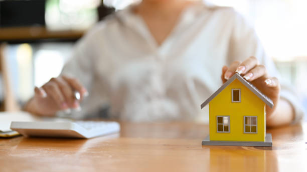 istock A beautiful yellow house model on a workspace table with female real estate agent 1397863004