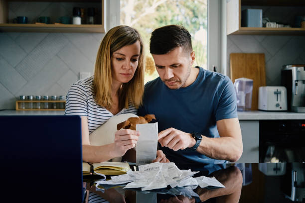Man And Woman Checking Payment Bills In The Kitchen At Home. Planning Family Budget Photo taken in Wroclaw, Poland cost of living stock pictures, royalty-free photos & images