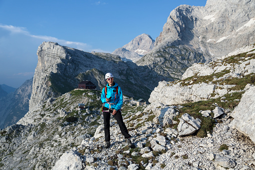 Young woman in mountain climbing gear standing high mountains.