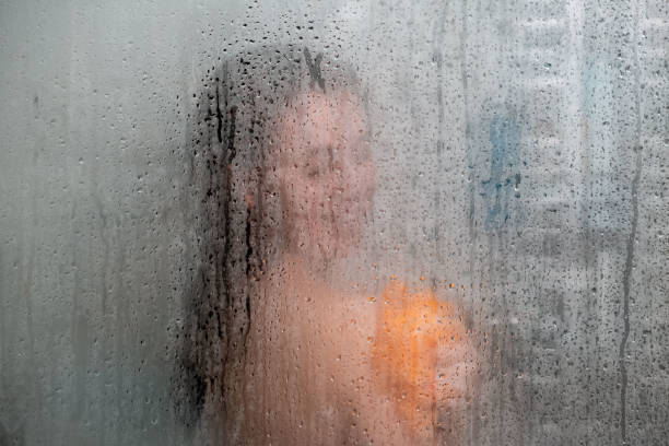 istock woman in shower view through glass covered with drops 1397868470