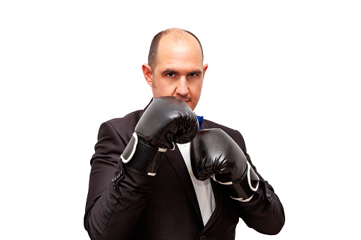 Waist up of with short hair caucasian young male in front of black background wearing glove who is serious and boxing and showing fist who is punching