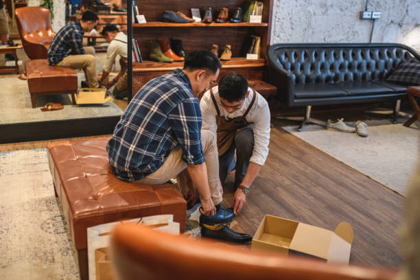 istock Young Asian Salesman Helping A Client Try On New Leather Shoes 1397870424