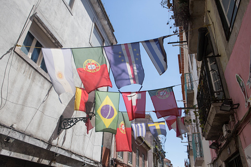 A picture of flags in a street in Lisbon, with buildings and the sky in the background