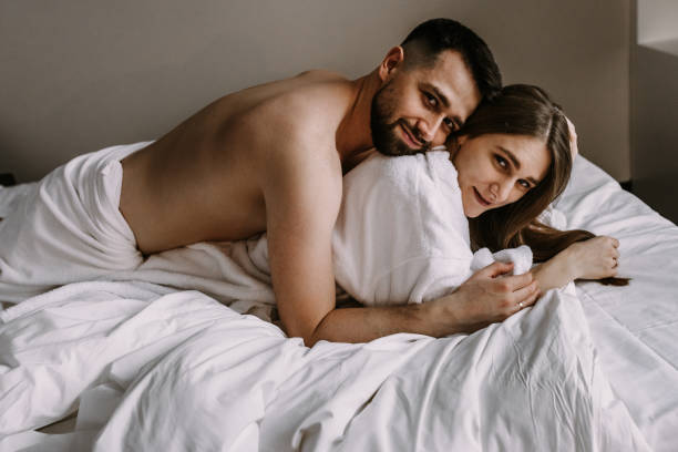 European couple hugging together while lying in bed at hotel stock photo